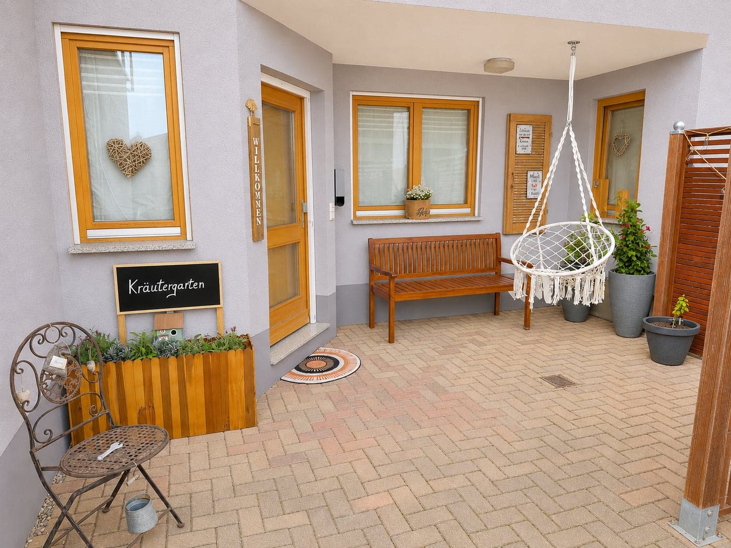 Terrasse mit Sitzbank, Makramee-Hängesessel und Kräutergarten