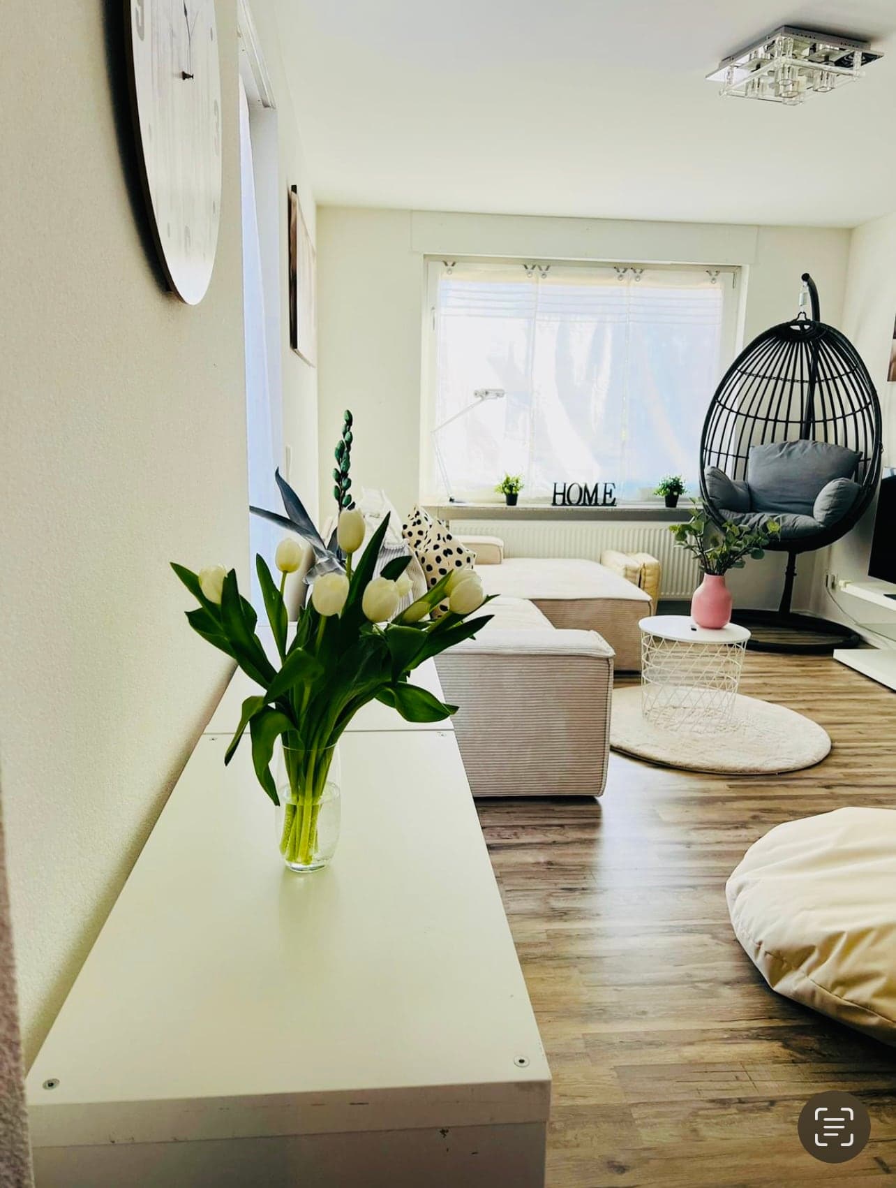 Heller Wohnbereich mit Hängesessel, Sofa und großen Fenstern